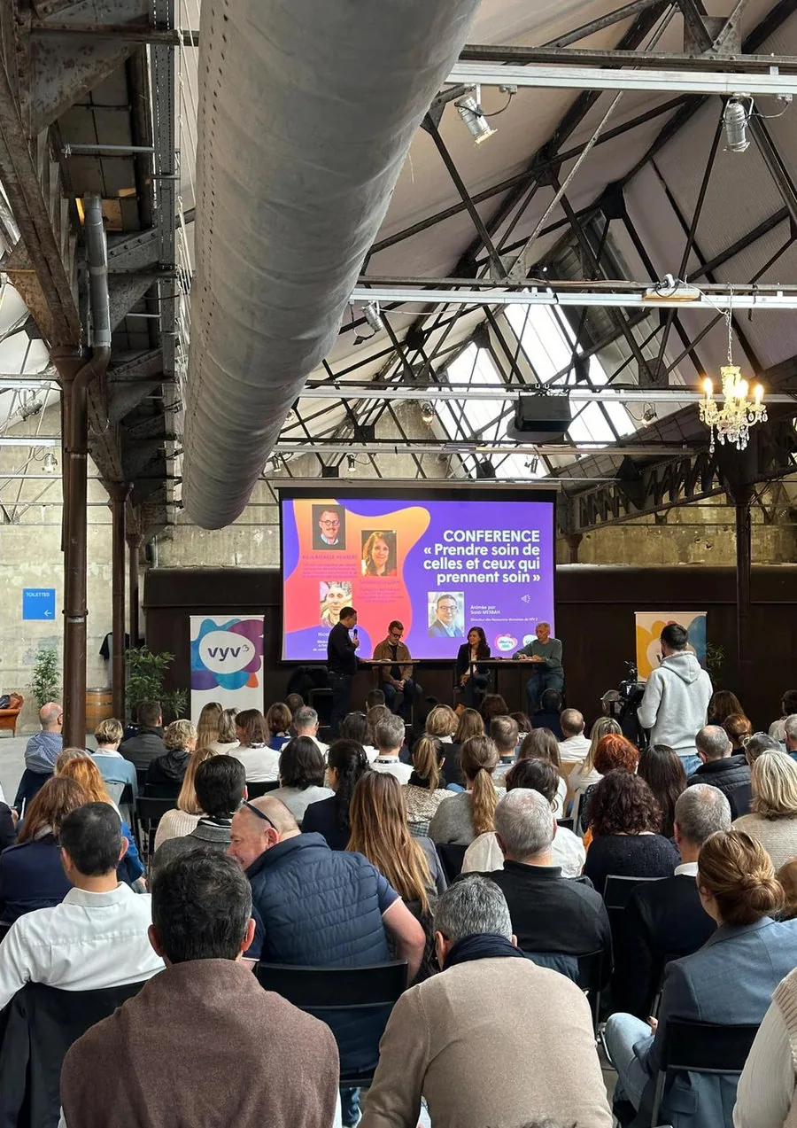 Plénière de convention dans une halle industrielle, écran et audience assise